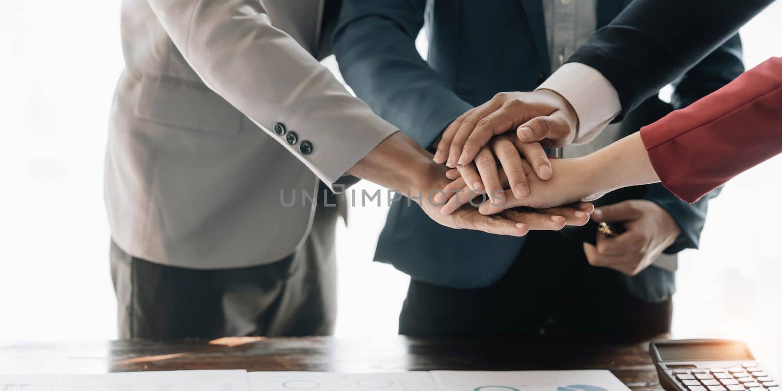 Group of business people putting their hands working together on wooden background in office. group support teamwork agreement concept