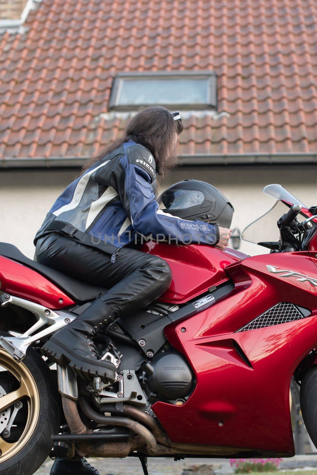 a young girl biker in a helmet and a moto suit on a red Honda goes on a trip, As,Belgium, May 16,2022 ,High quality photo