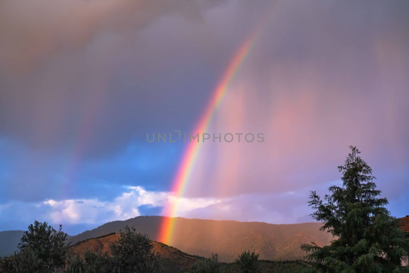 Rays of the sun breaking through the stormy sky, forming a marvelous rainbow. High quality photo
