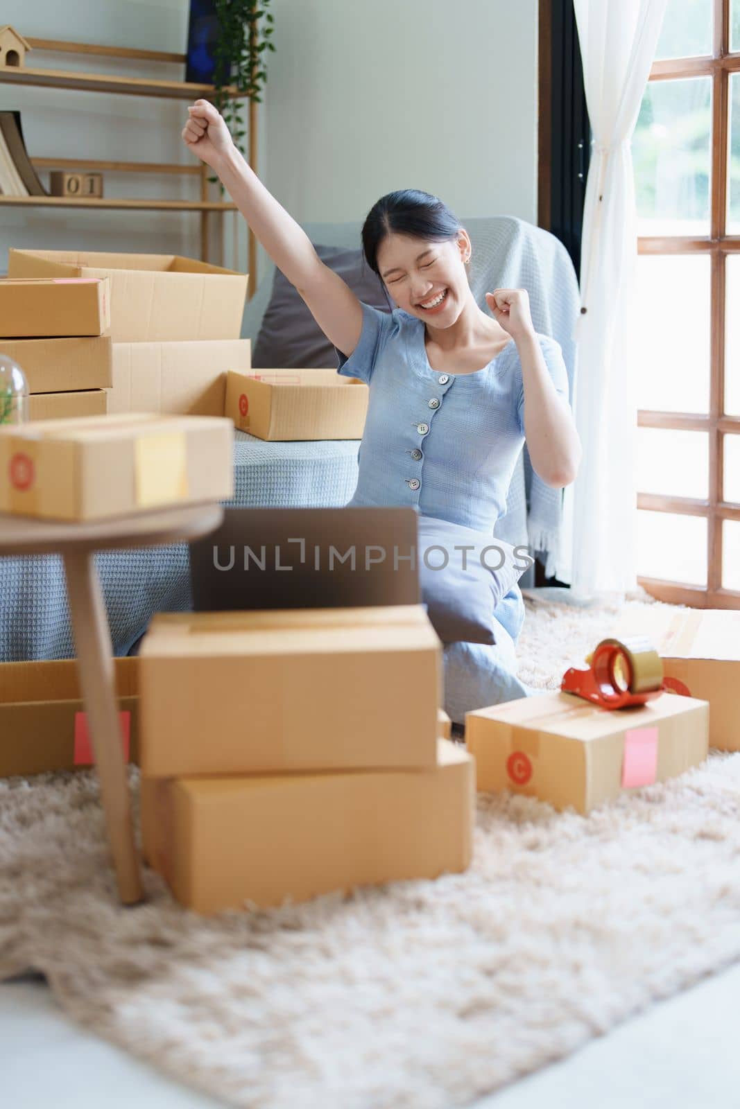 Starting small business entrepreneur of independent Asian woman smiling using computer laptop with cheerful success of online marketing package box items and SME delivery concept.