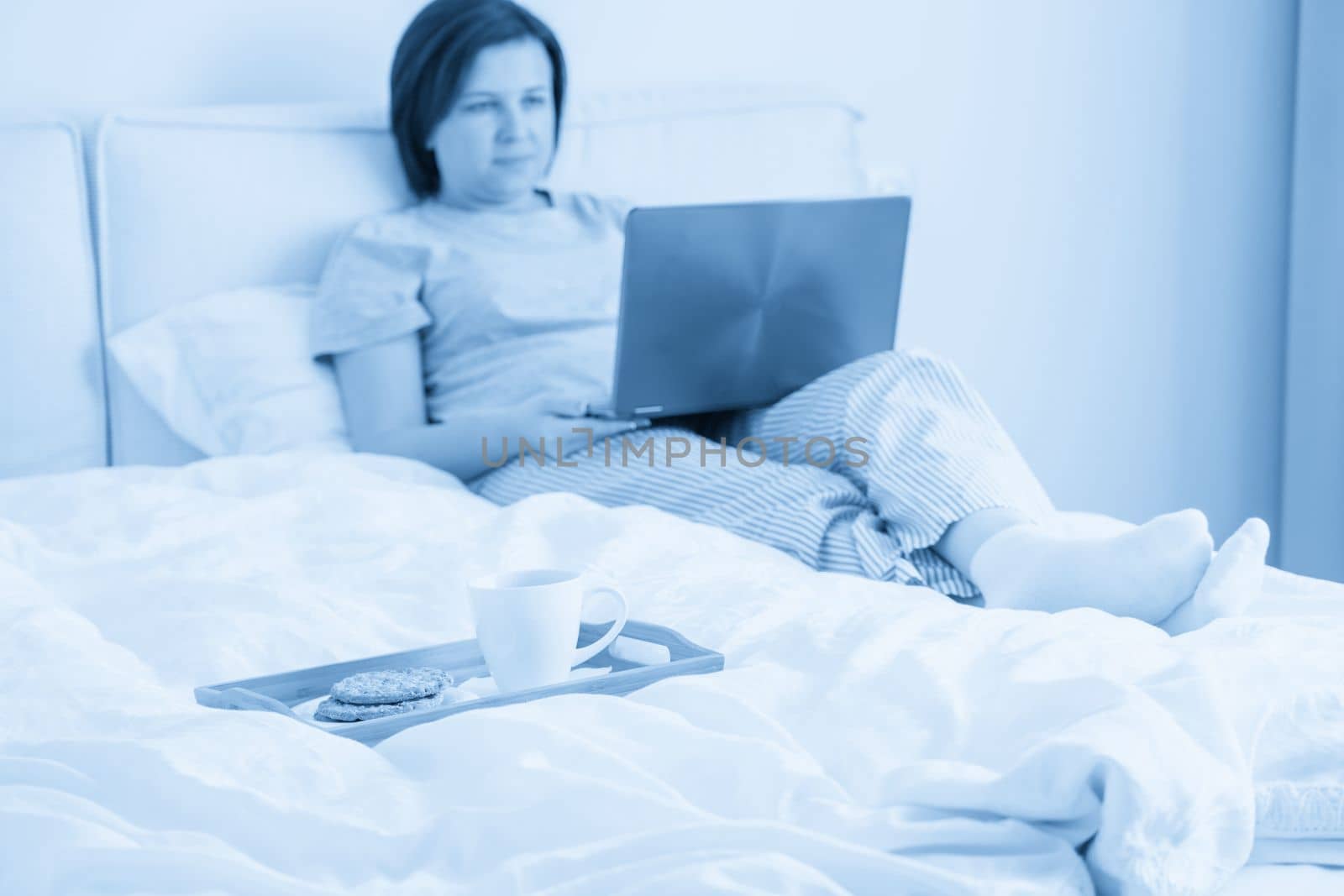 Woman in bed with laptop and a breakfast
