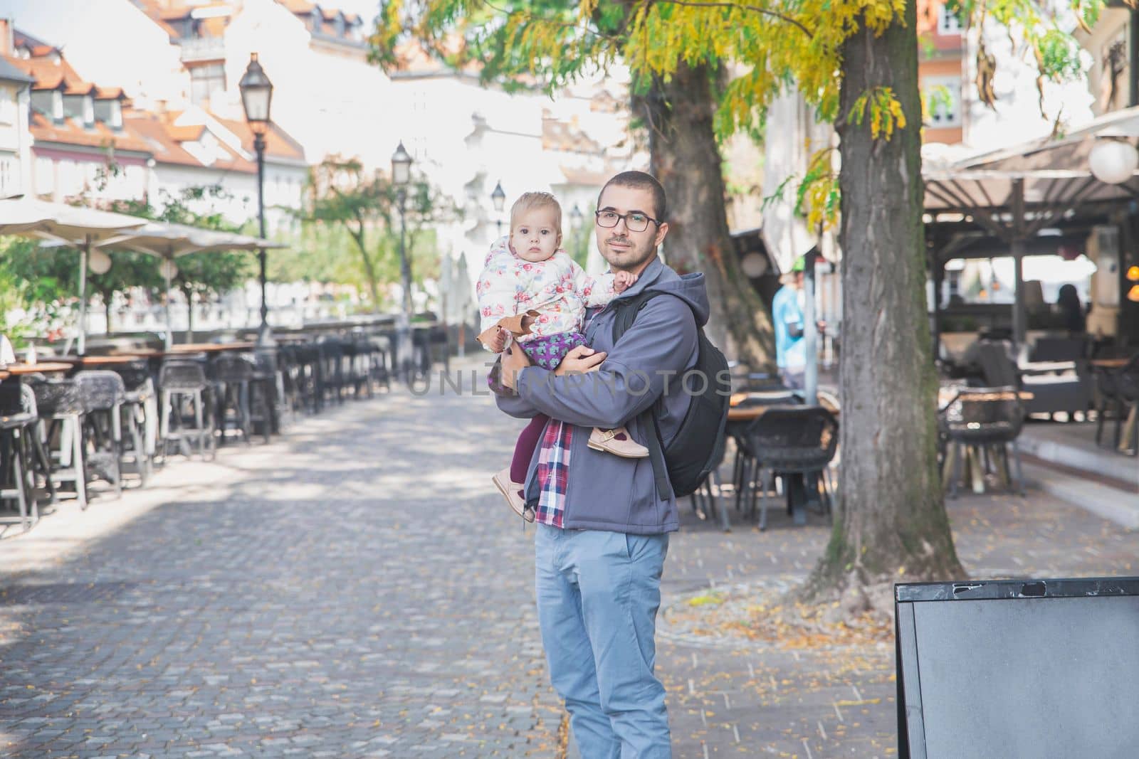 young dad with a charming daughter in his arms in Ljubljana.