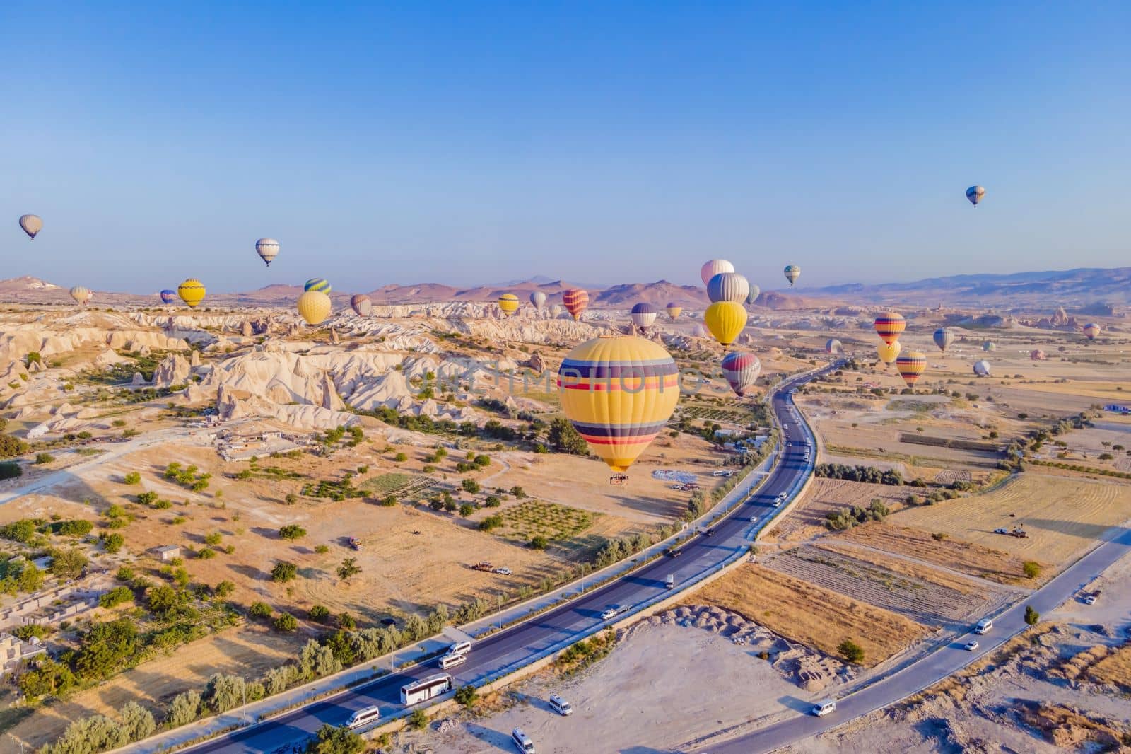 Colorful hot air balloons flying over at fairy chimneys valley in Nevsehir, Goreme, Cappadocia Turkey. Spectacular panoramic drone view of the underground city and ballooning tourism. High quality.