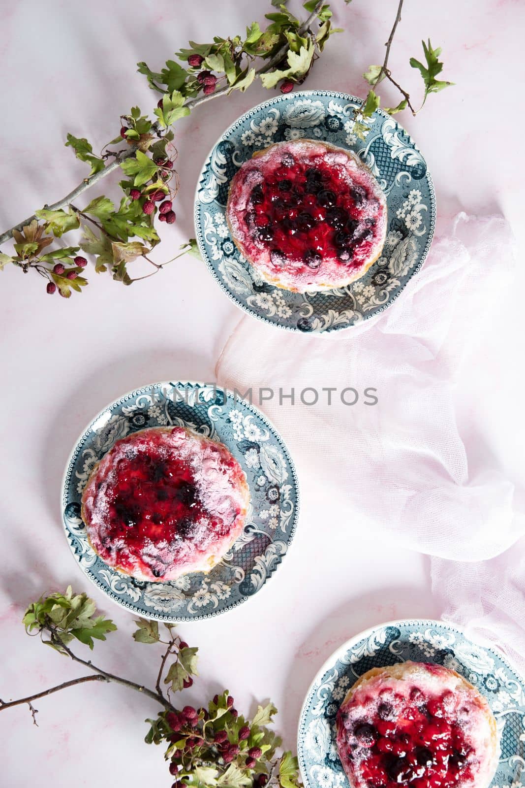 delicious cake with cream and wild berries, sprinkled with powdered sugar, top view, on a pink marble background. High quality photo