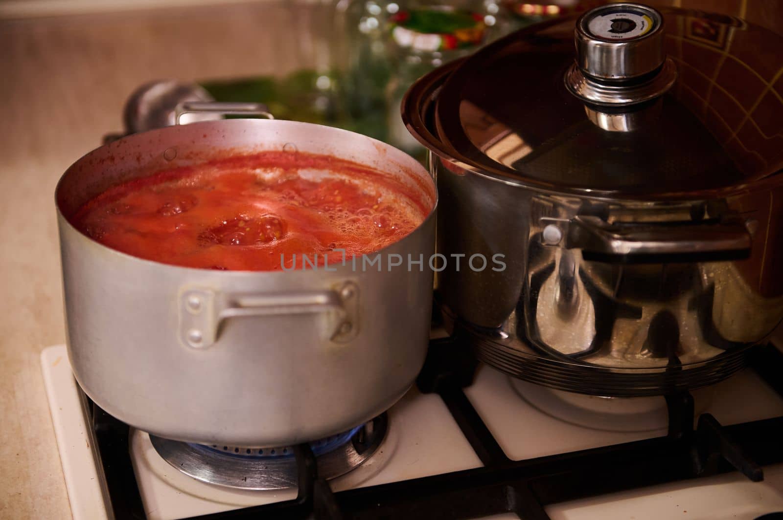 Top view stirring boiling tomato juice, preparing homemade passata from ripe organic juicy tomatoes, according to traditional family recipe, in the kitchen at home. Canning food. Step-by-step recipe