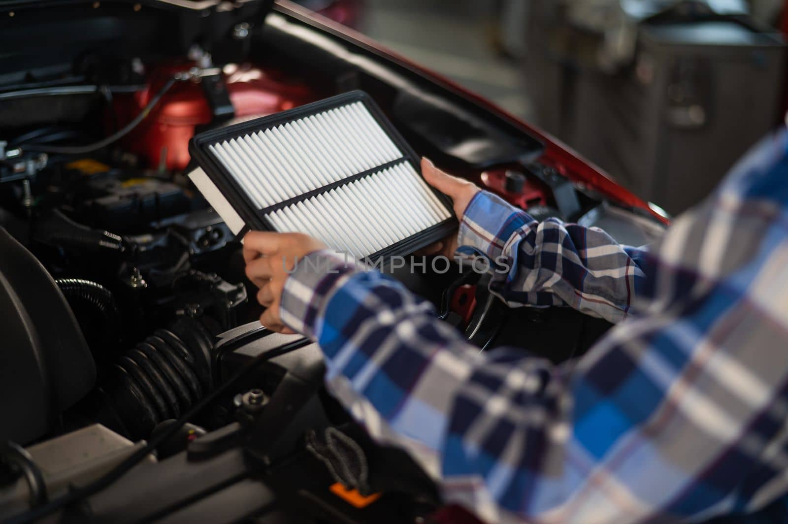 Caucasian female auto mechanic changes the engine air filter in the car