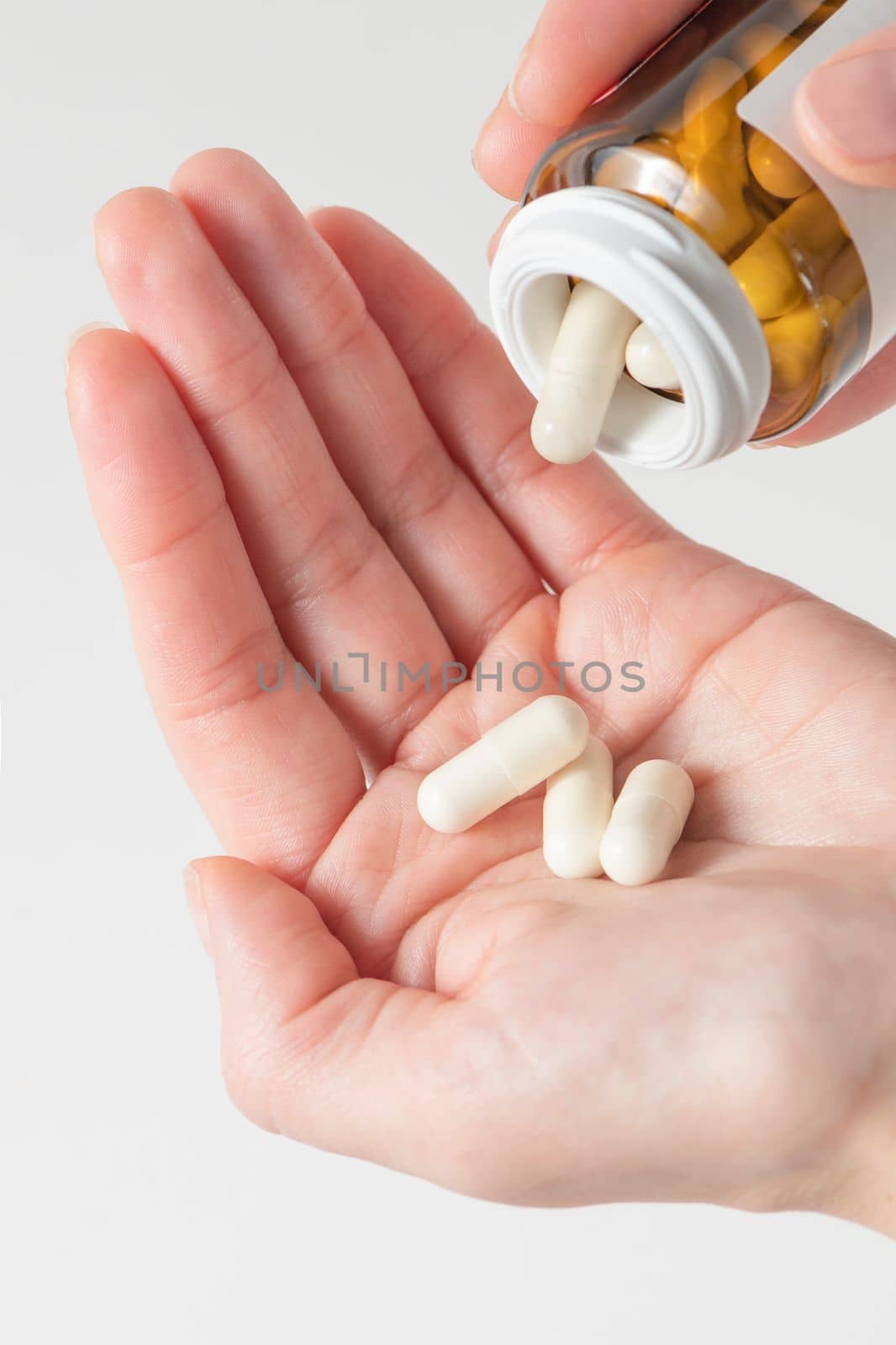 A woman holds pills in her hand, pours capsules with painkillers into her hand to get rid of pain. Taking pills or antibiotics, treating various diseases