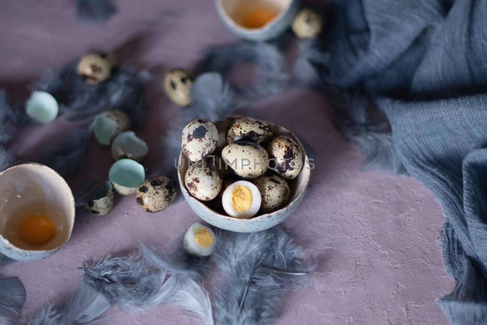quail eggs in ceramic vases, gray feathers on the table, easter still life, natural food, diet and antioxidants, dark key and shallow depth of field. High quality photo