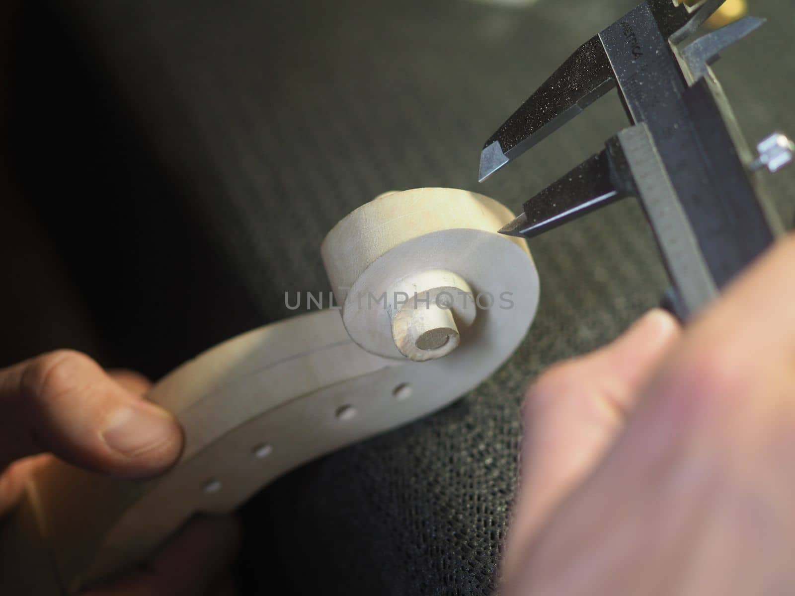 violin maker using a meter to shape and accurate measure fiddle scroll