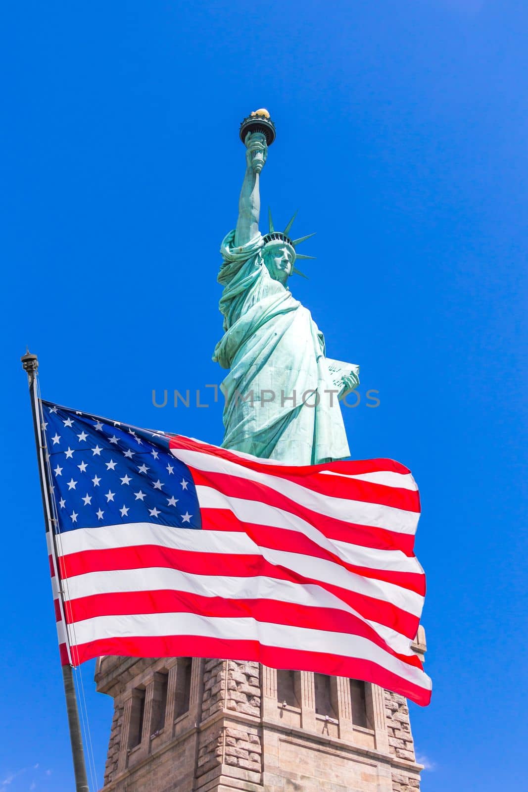 American flag waving on the wind against Statue of Liberty