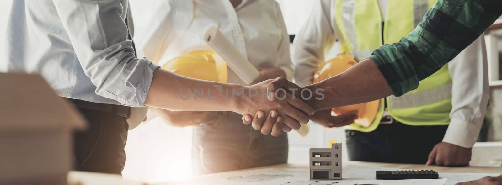 Professional Asian male engineer shaking hands with male architect after the meeting..