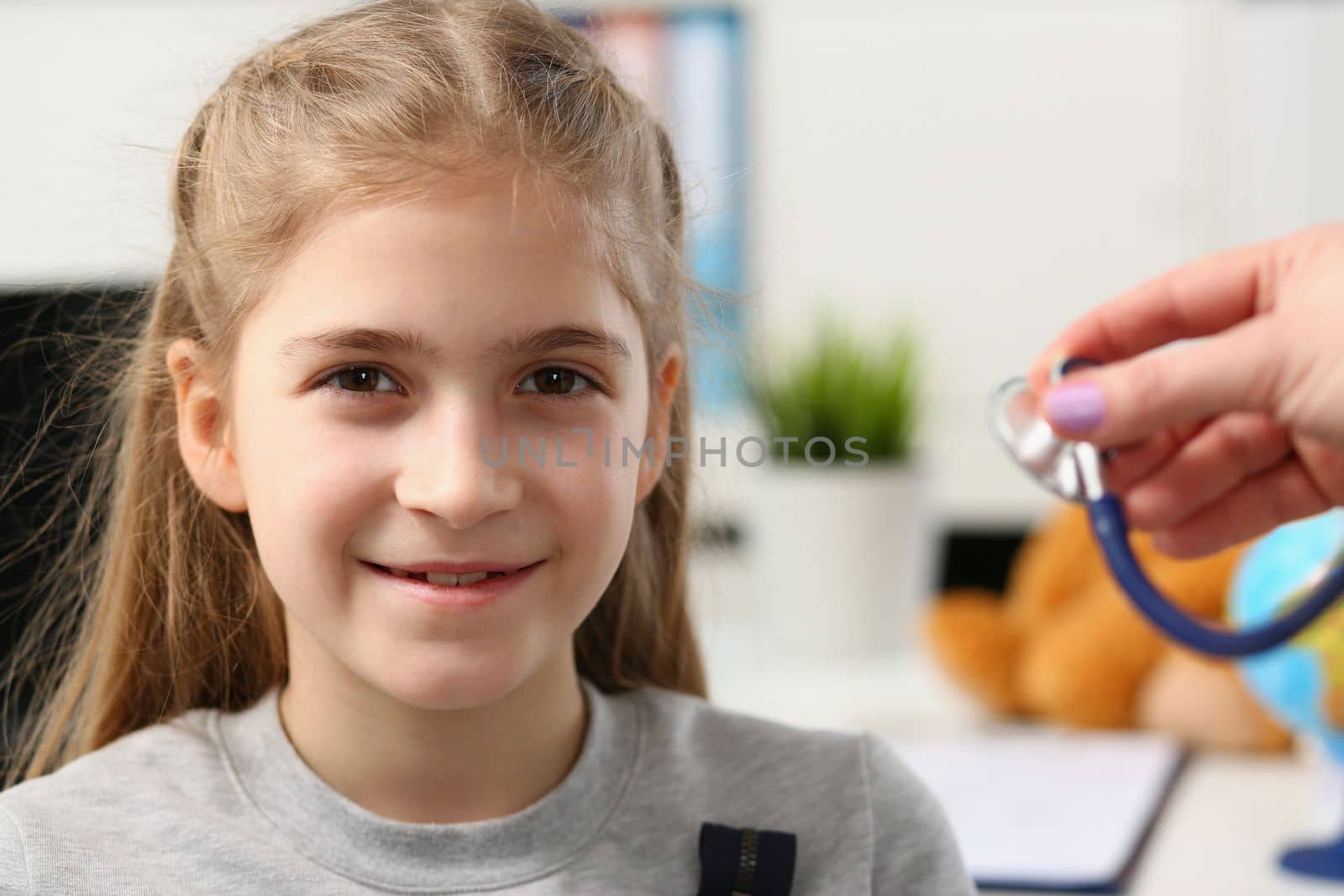 Portrait of a beautiful child girl and doctor hand with stethoscope. Medical baby examination of child concept