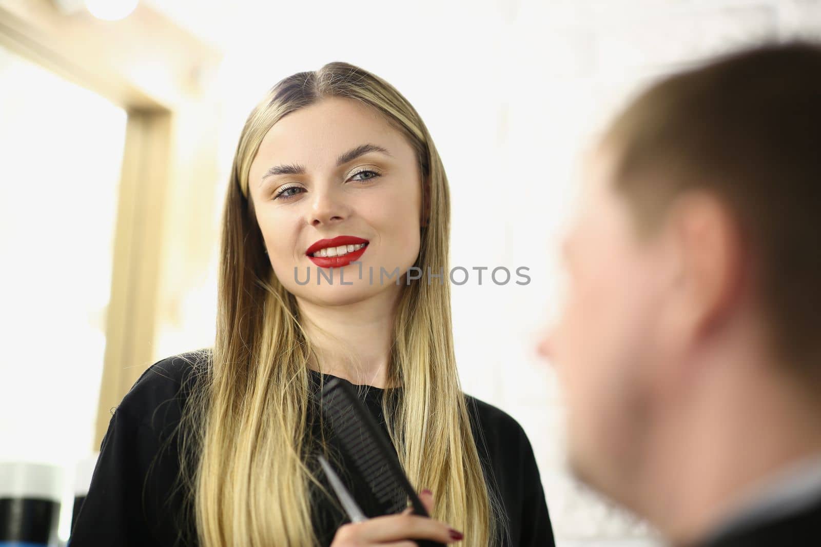 Portrait of young beautiful woman hairdresser communicates in beauty salon with client. Hairdressing services stylists concept