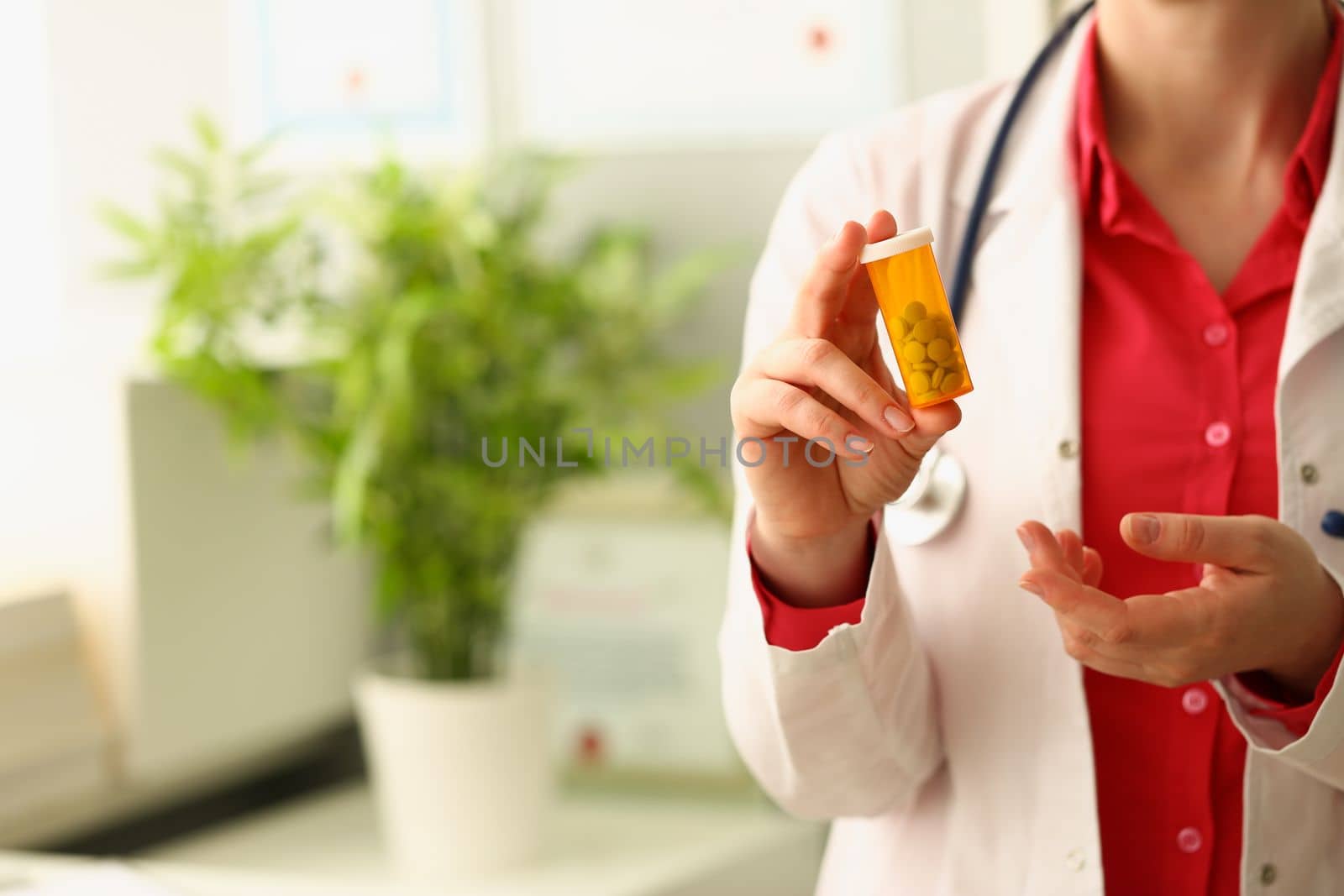 Doctor holds jar of medical capsules pills in clinic. Prescribing medications by therapist