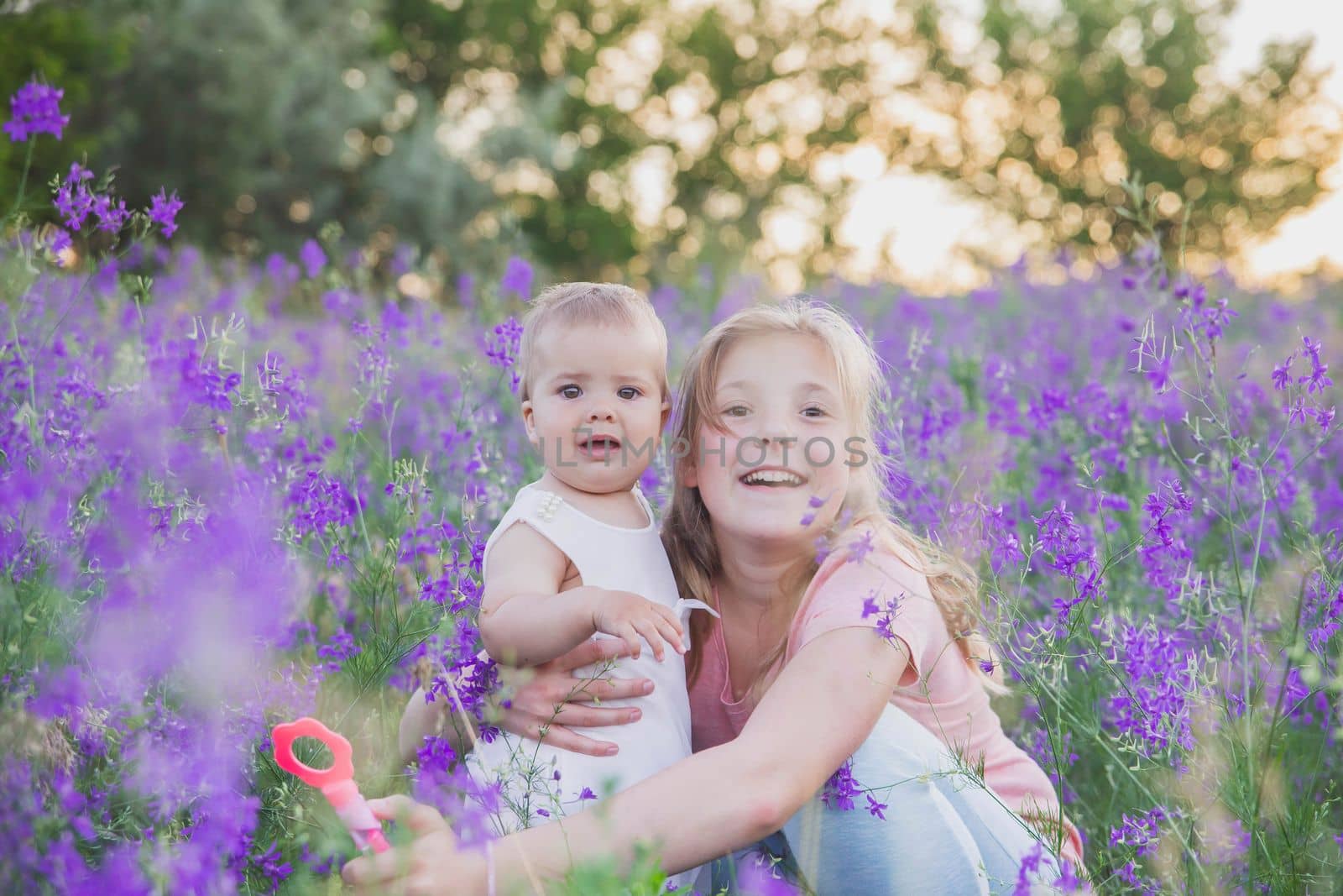 Two blond sisters in flowers at sunset.