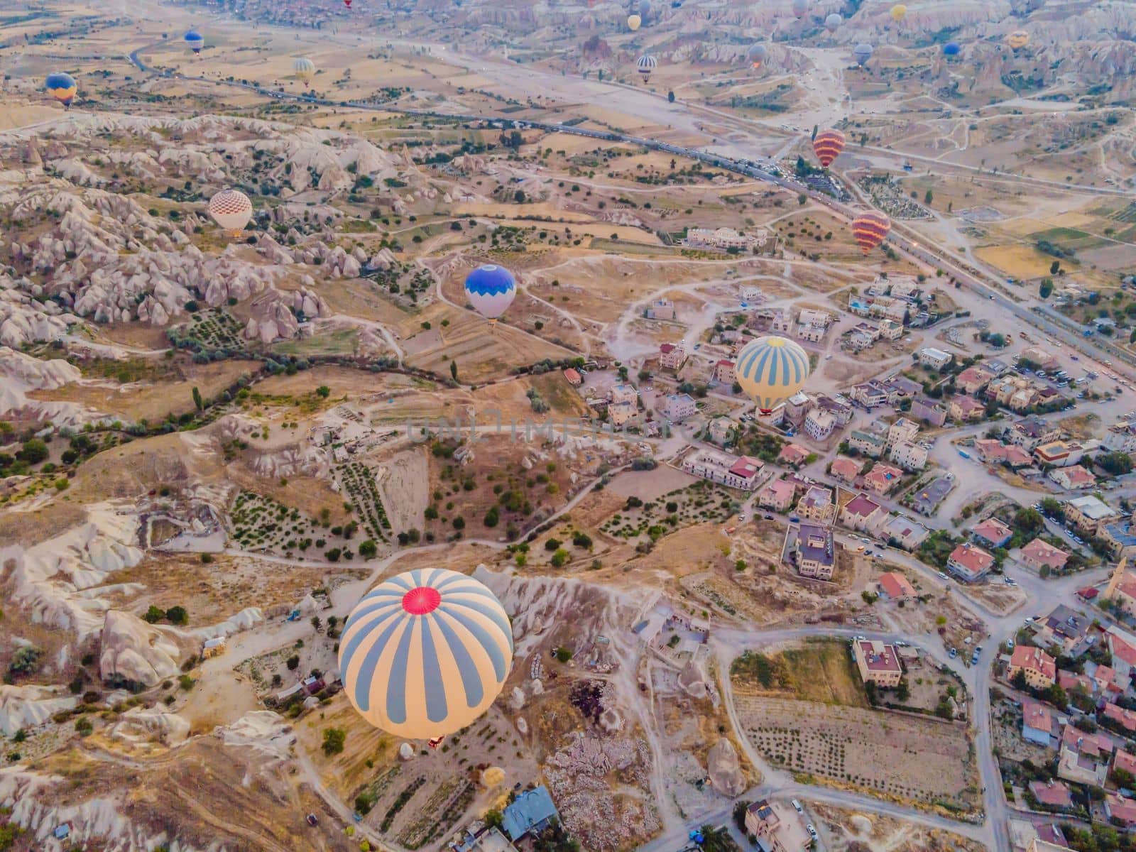 Colorful hot air balloons flying over at fairy chimneys valley in Nevsehir, Goreme, Cappadocia Turkey. Spectacular panoramic drone view of the underground city and ballooning tourism. High quality by galitskaya