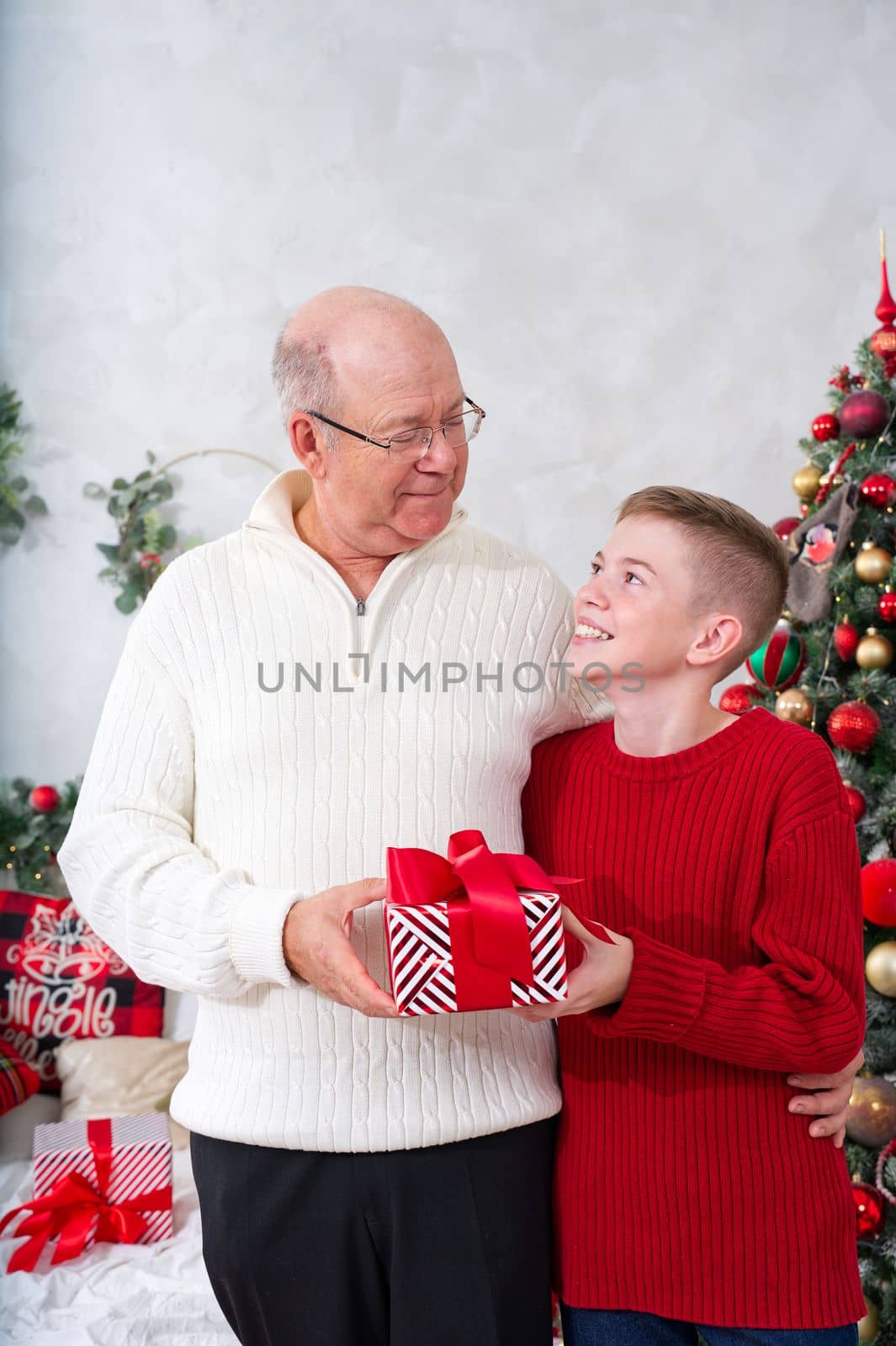 Happy Grandson giving grandpa a Christmas present. Cute little boy is giving his father a gift and smiling. Christmas wonder.