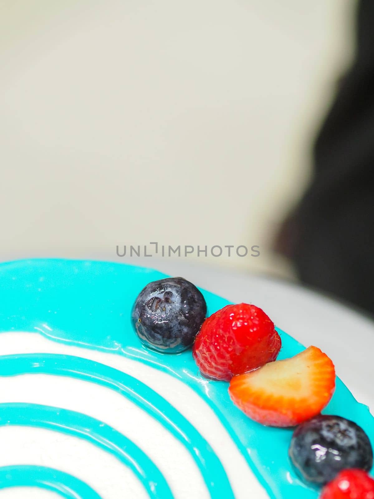 hand pastry chef designer topping a frosted white cake with pastel light blue drip filling bag by verbano