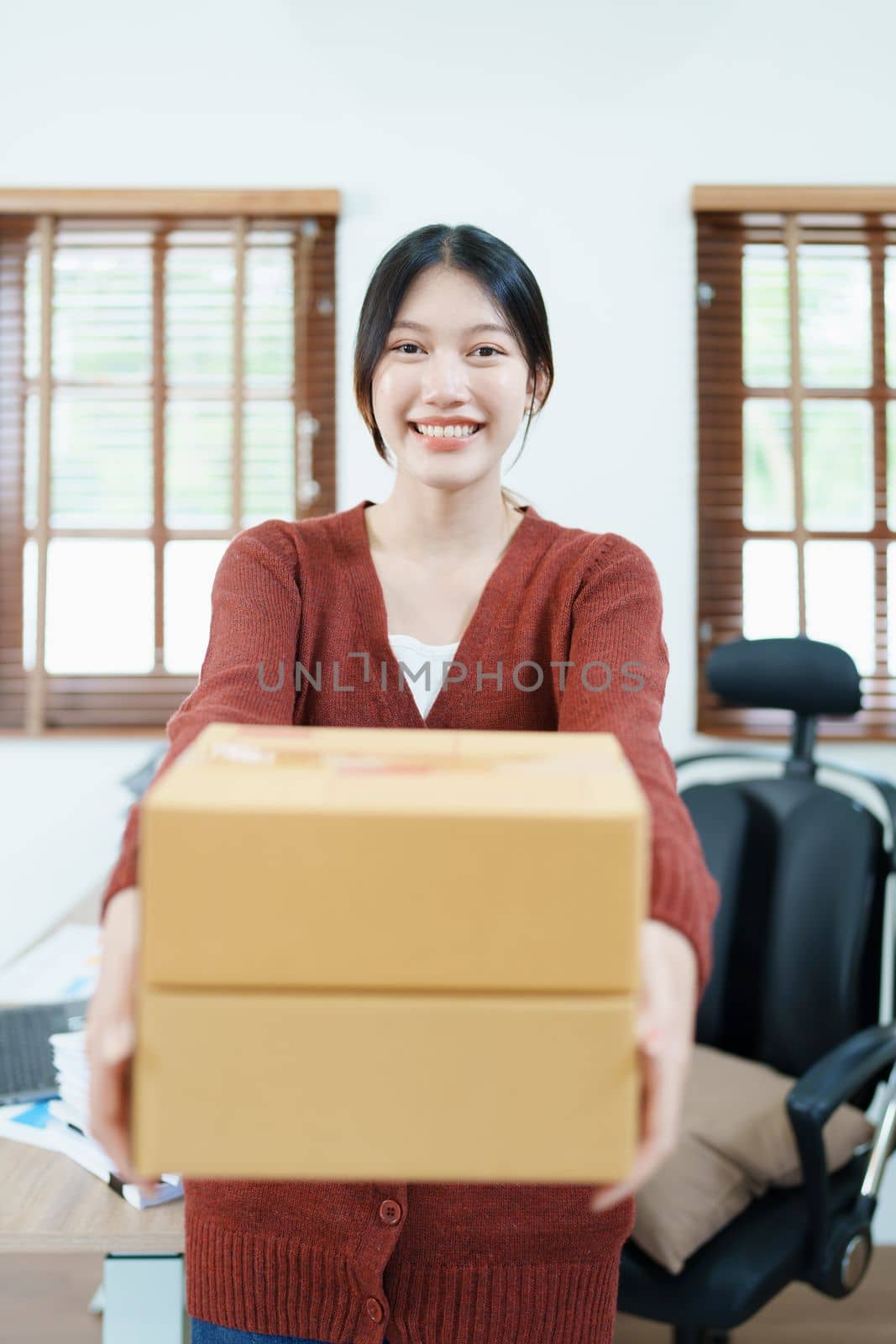 Starting small business entrepreneur of independent Asian woman smiling using computer laptop with cheerful success of online marketing package box items and SME delivery concept by Manastrong