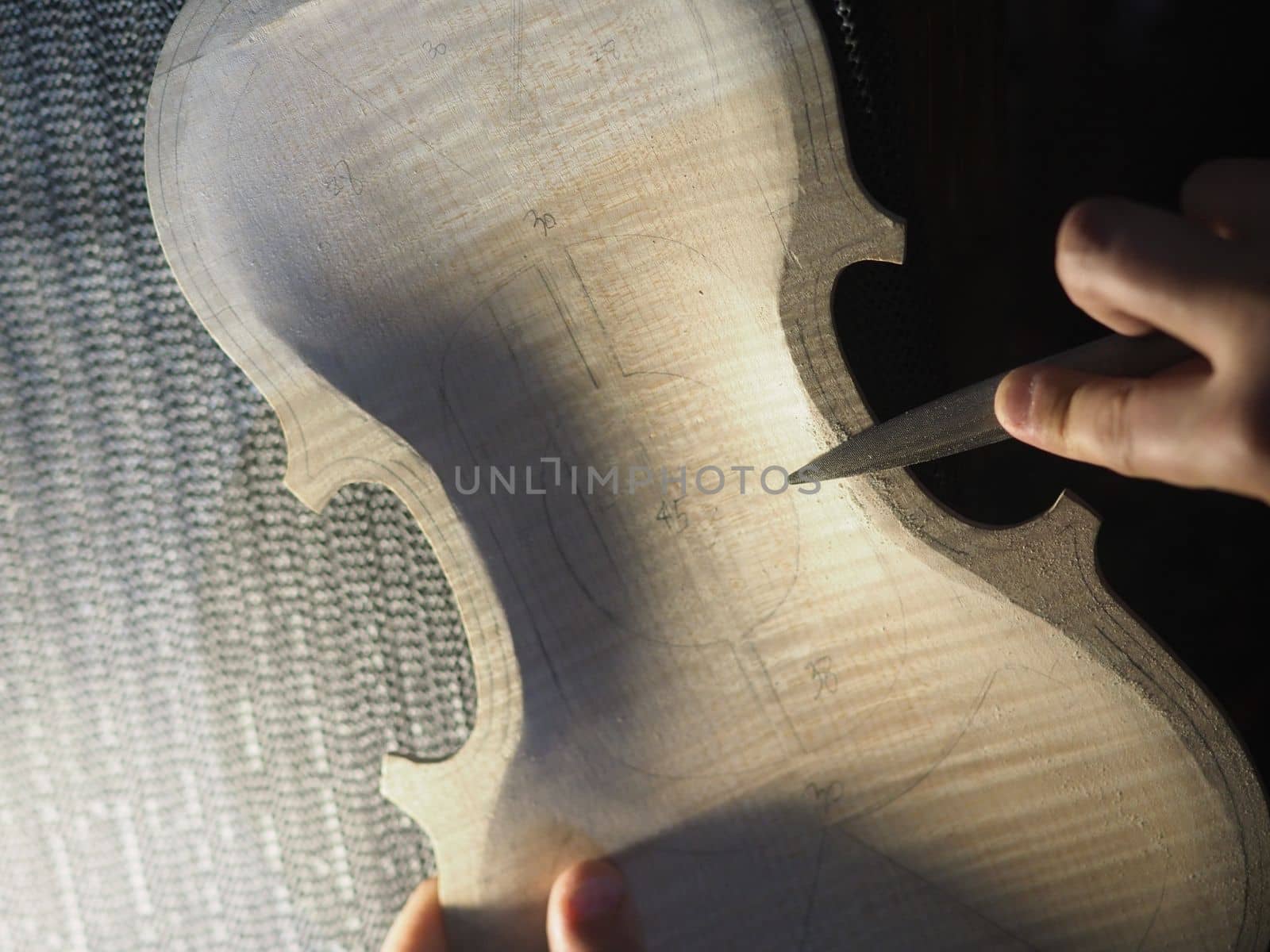 artisan maker drilling and carving on fiddle plate outline