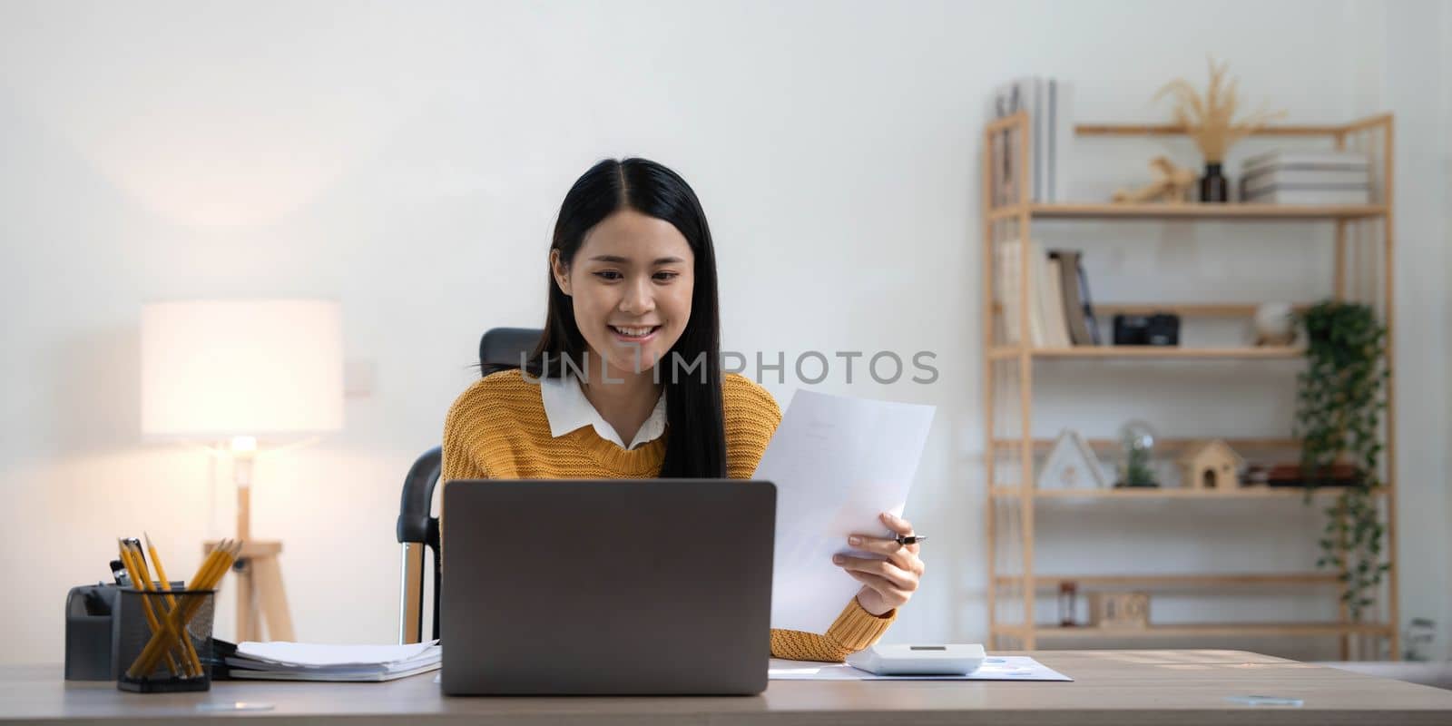 Portrait of Young Asian woman hand freelancer is working her job on computer tablet in modern home. Doing accounting analysis report real estate investment data, Financial and tax systems concept..