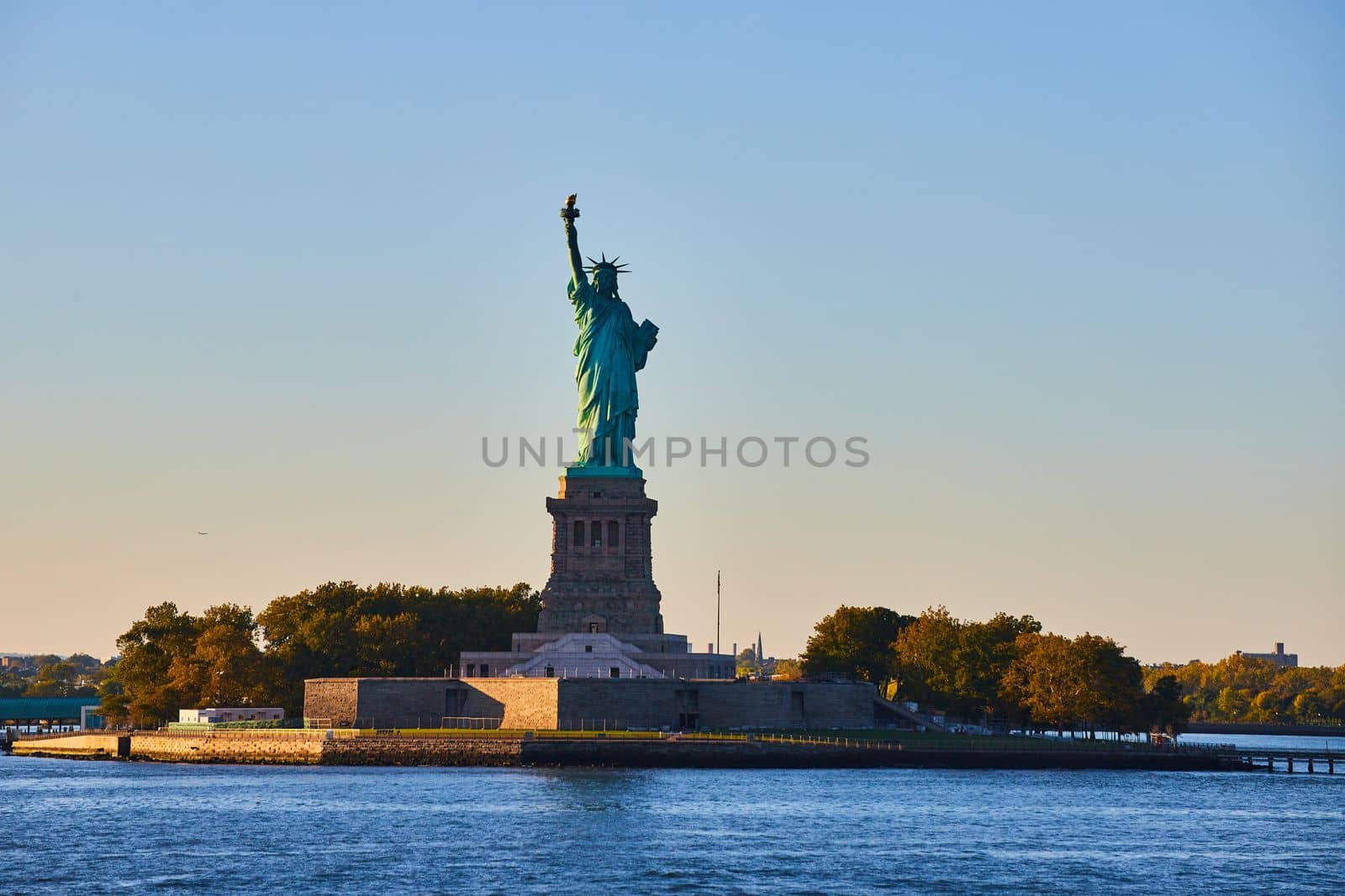 Image of Island with Statue of Liberty in soft golden light with light filling in left side