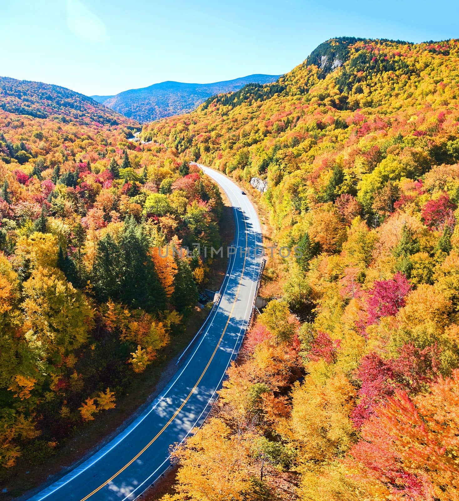 Image of Road winding through New Hampshire mountains in peak fall with stunning foliage