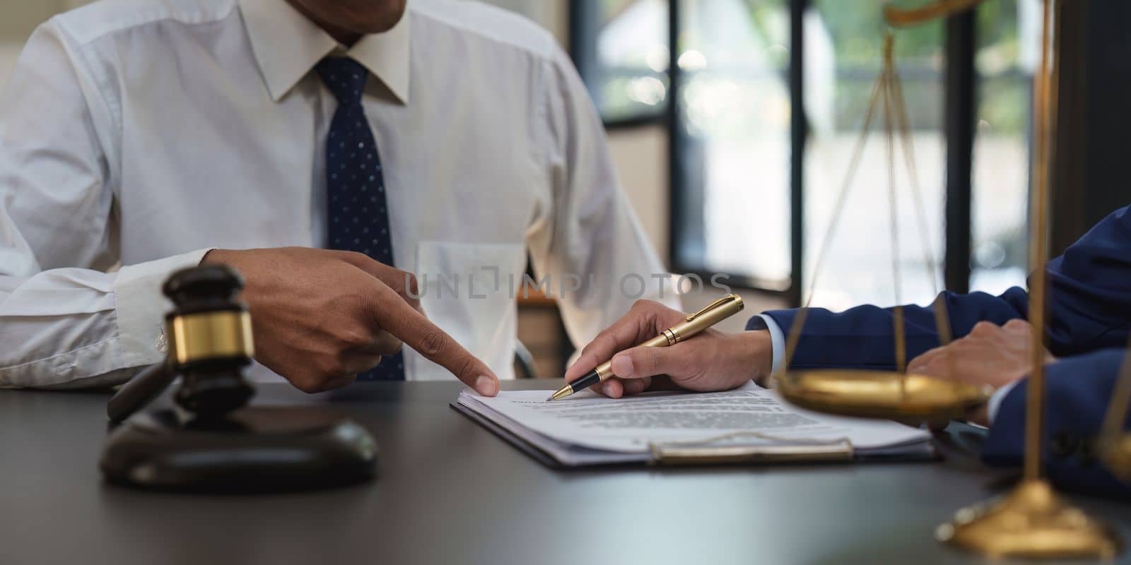 Business people and lawyers discussing contract papers with brass scale on wooden desk in office. Law, legal services, advice, Justice concept by itchaznong