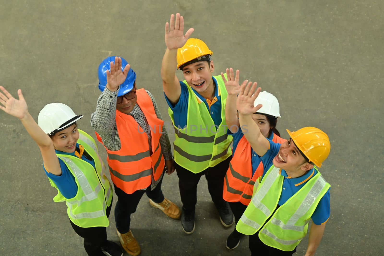 Overhead view of diverse warehouse workers celebrating success together. Manufacture storehouse occupation concept.