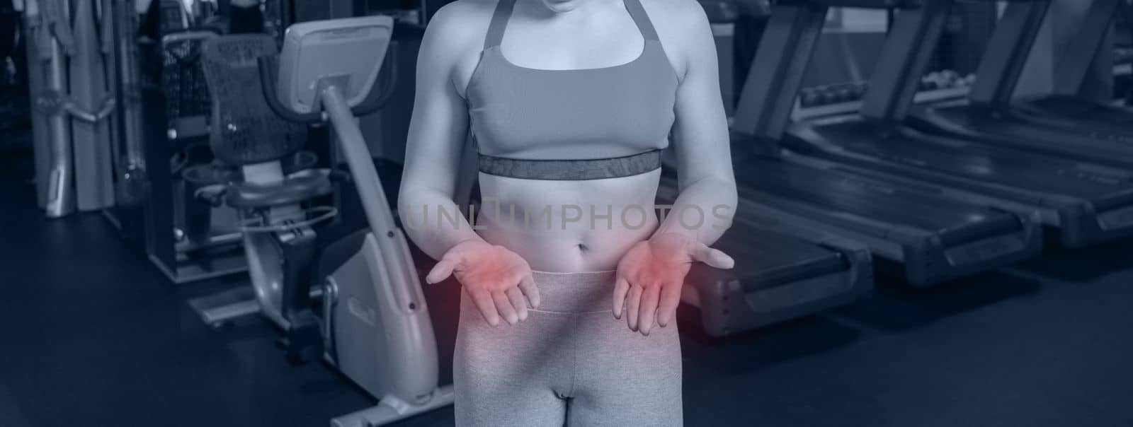 Young woman in sportswear having ache on palms after training in gym by Mariakray