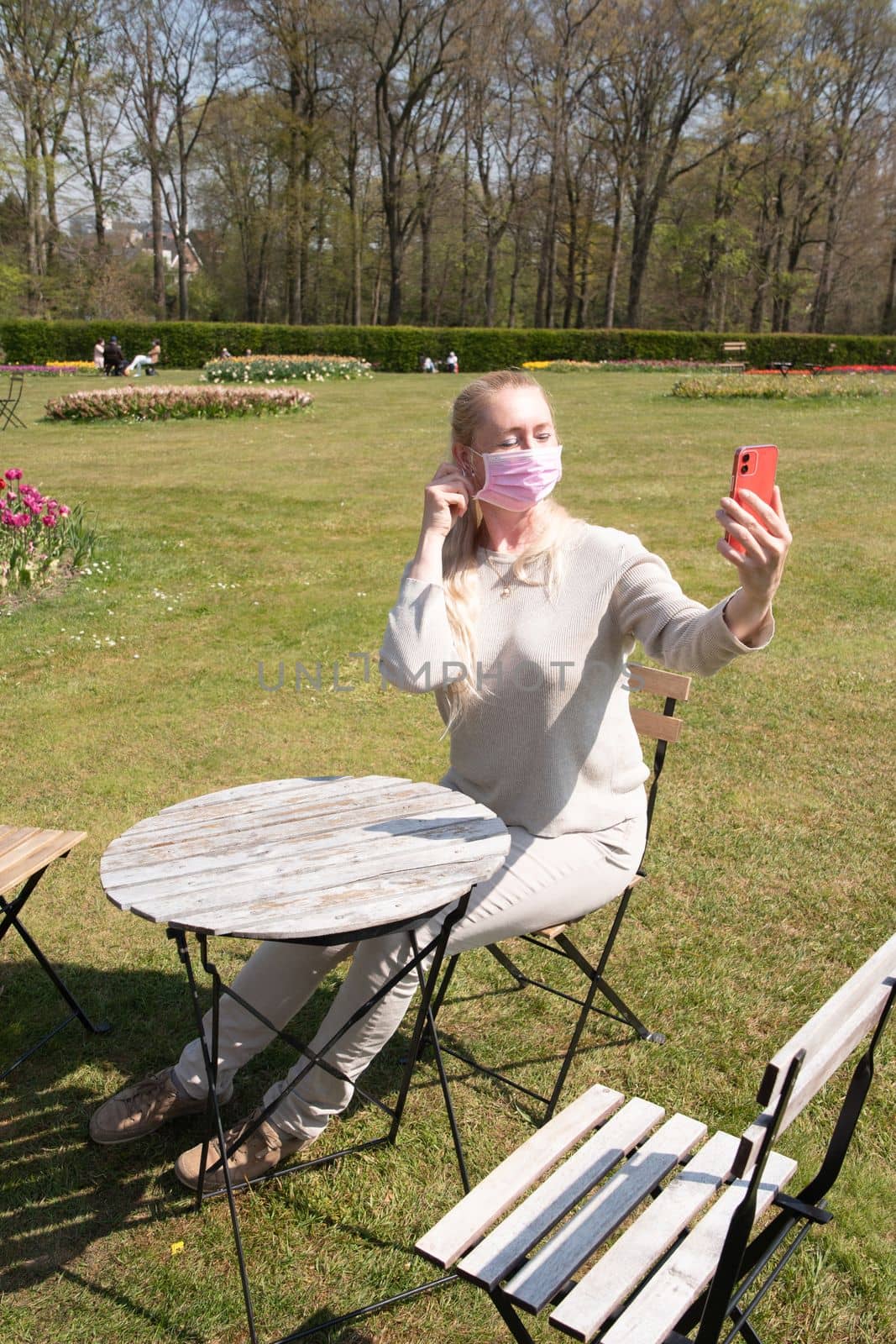 young woman in a protective mask takes a selfie with blooming sprimg tulips by KaterinaDalemans