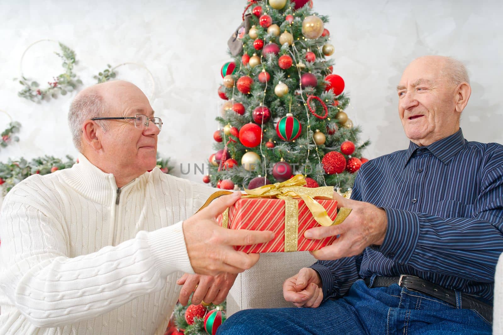 Son giving gift box to father. Man giving Christmas present to elderly father. Happy people family concept by PhotoTime