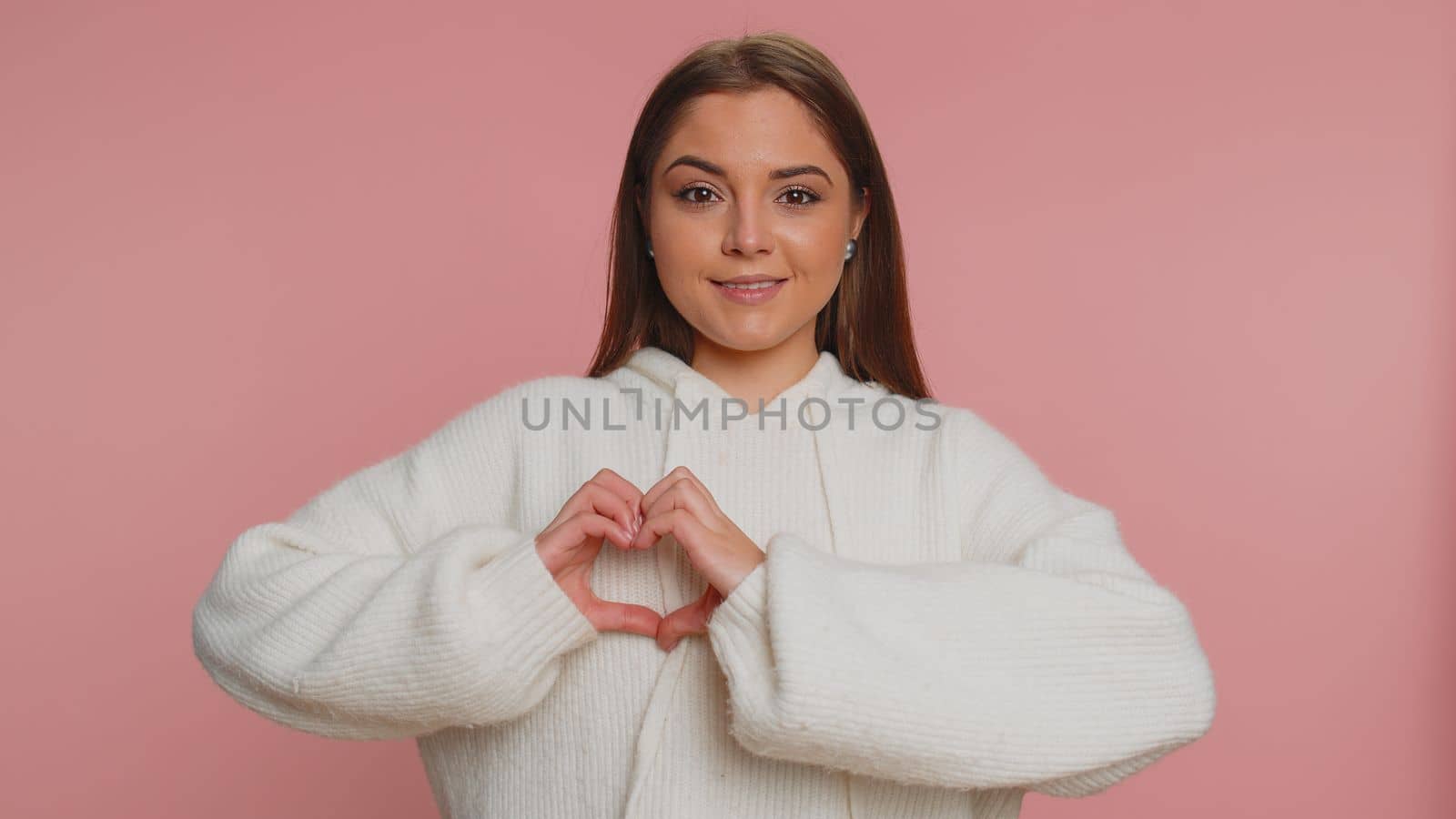 Smiling pretty woman makes heart gesture demonstrates love sign expresses good feelings and sympathy by efuror
