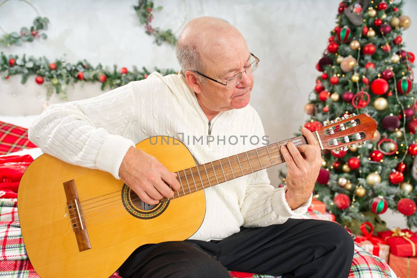 Father playing guitar during christmas. Happy man 60s playing guitar christmas songs. by PhotoTime