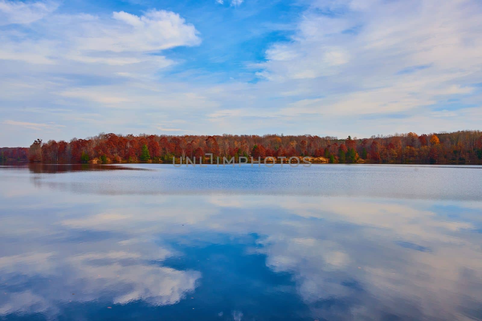 Image of Crystal clear lake surface with fall forests lining the coast in Michigan