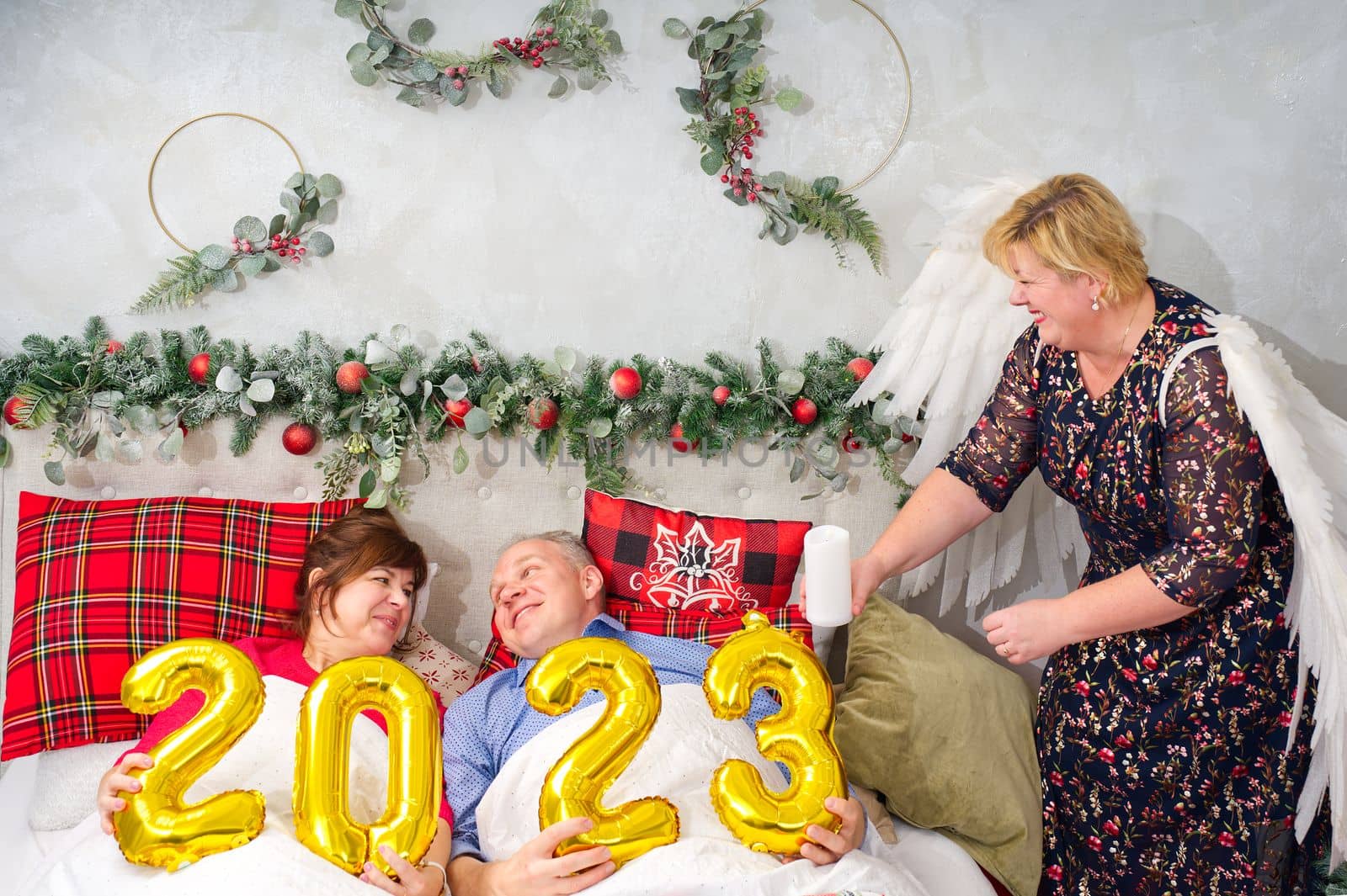 beautiful couple laying in bed, planning to have a baby. Christmas and happy New Year wishes with numbers 2023. Woman with angel wings, Christmas wonder.