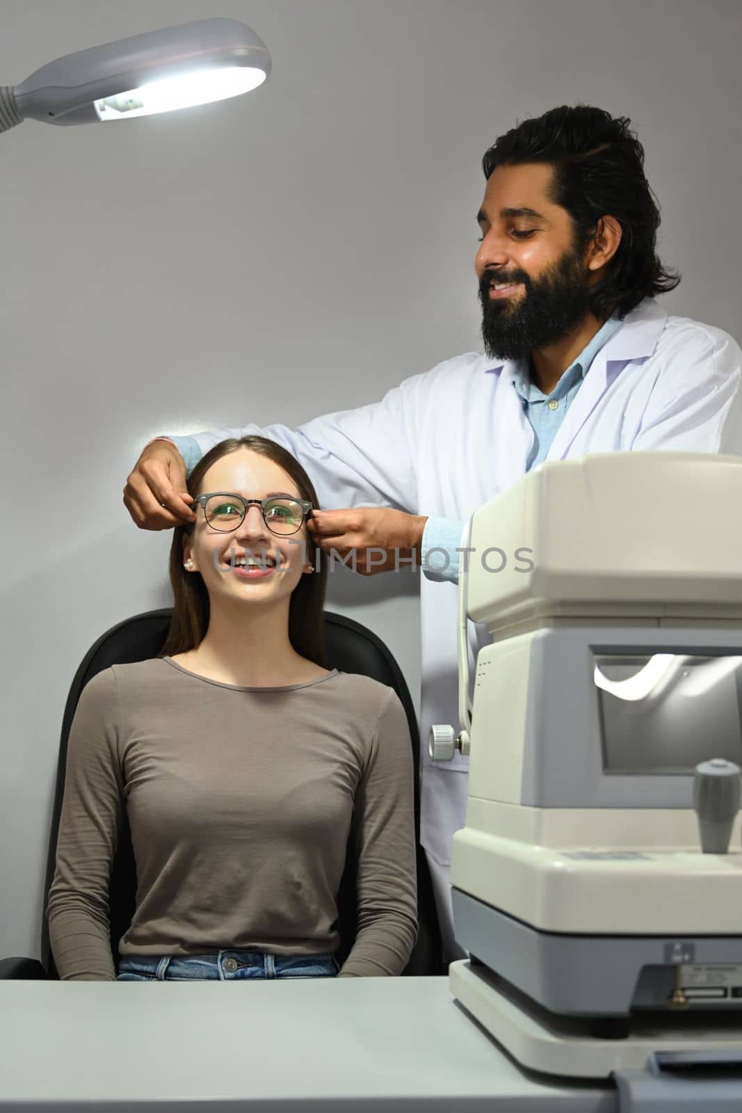 Happy caucasian woman testing new glasses with optometrist in optical store. Eyesight and vision concept.