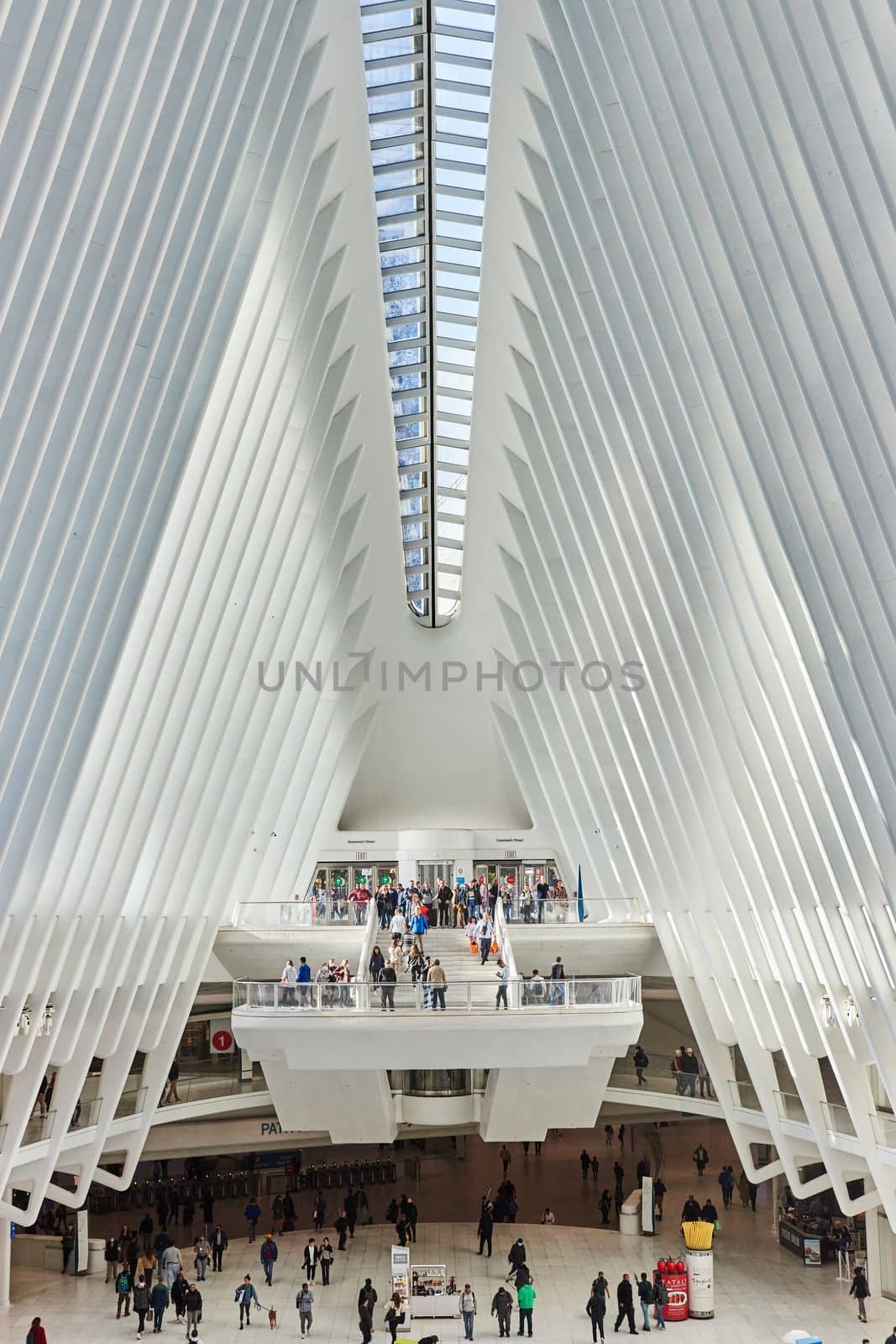 Image of Huge open white and glass subway terminal with light hitting overlook spot filled with tourists