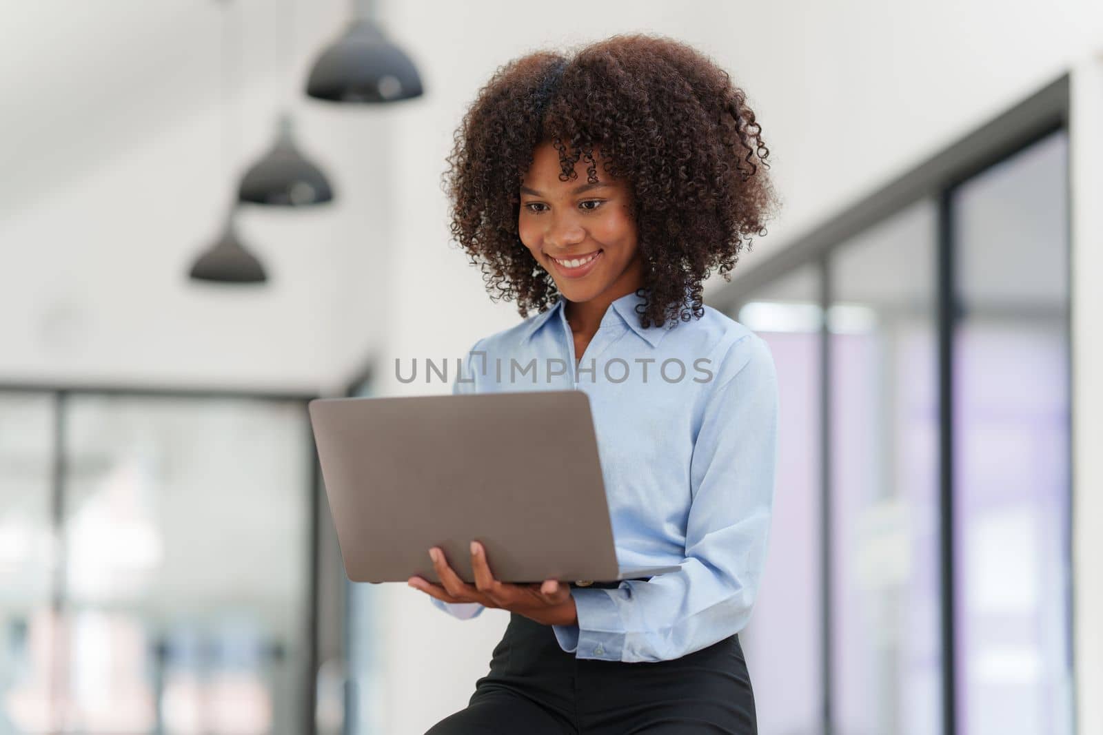 Portrait young african american businesswoman looking at laptop. Woman reading news, report or email. Online problem, finance mistake, troubleshooting.