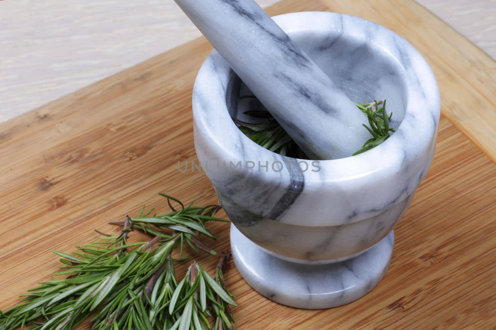 Rosemary herb being ground in a mortar and pestle from above