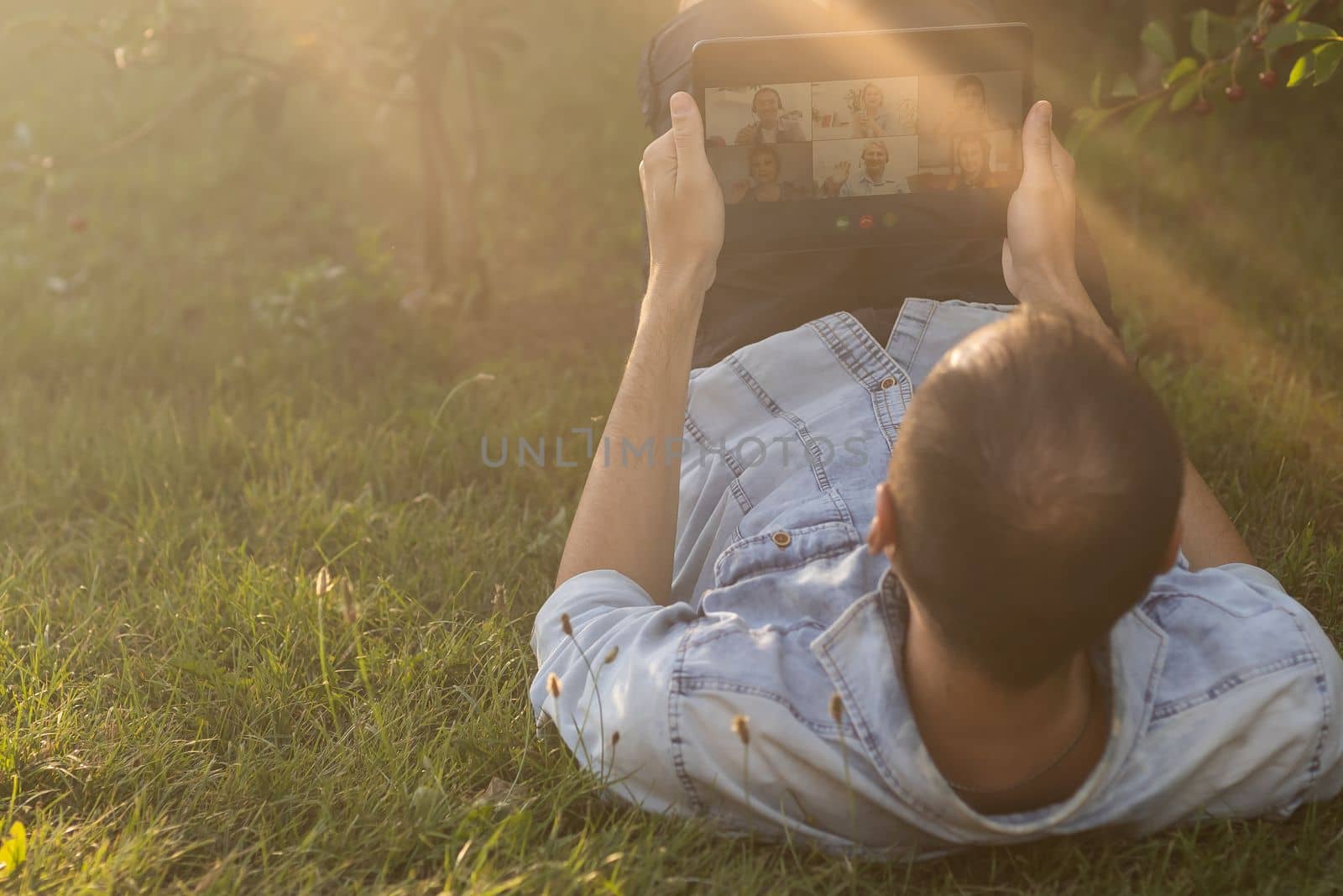 Young man in the garden in summer on the laptop computer while chatting online as a freelancer. by Andelov13