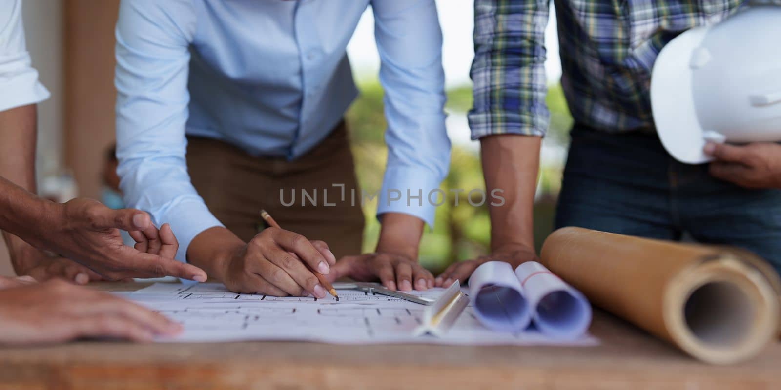 Architect team working with blueprints for architectural plan, engineer sketching a construction project, green energy concept.