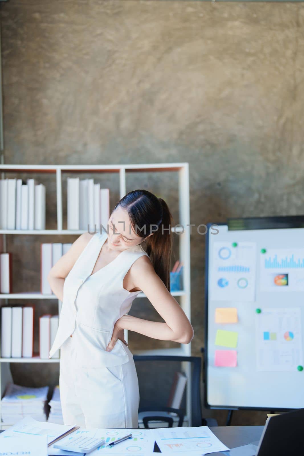 Portrait of a young Asian woman suffering from acute back pain from sitting for a long time at work