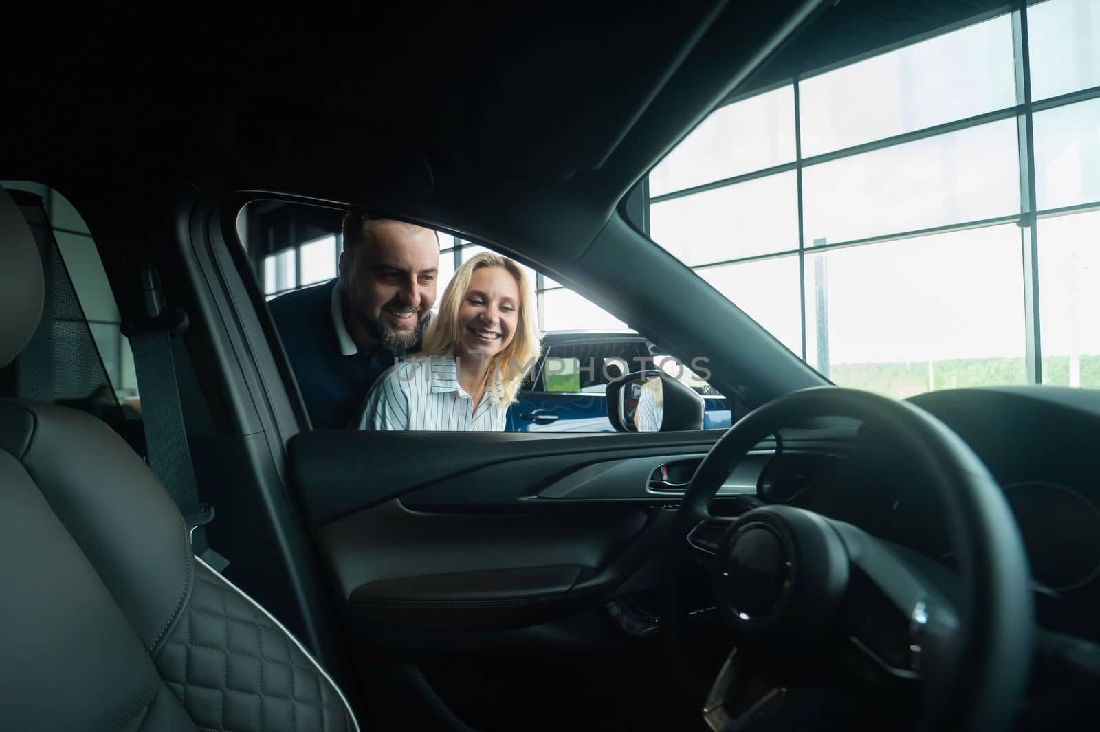 Caucasian family couple looking out the car window in a car dealership. by mrwed54