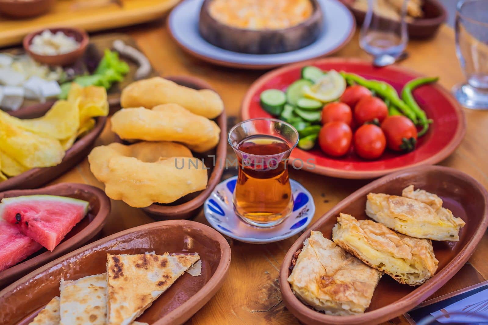 Turkish breakfast table. Pastries. Vegetables. Olives. Cheeses, fried eggs. Jams, tea in copper pot and tulip glasses. Wide composition.