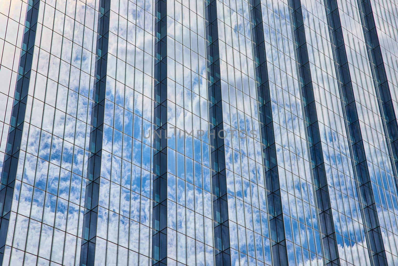 Detail of huge glass skyscraper reflecting blue sky and clouds by njproductions