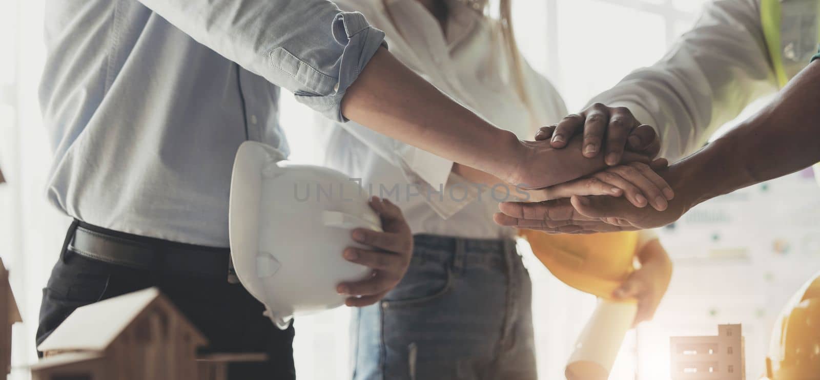 Businessmen and engineers join hands to build successful projects. Teamwork concept...