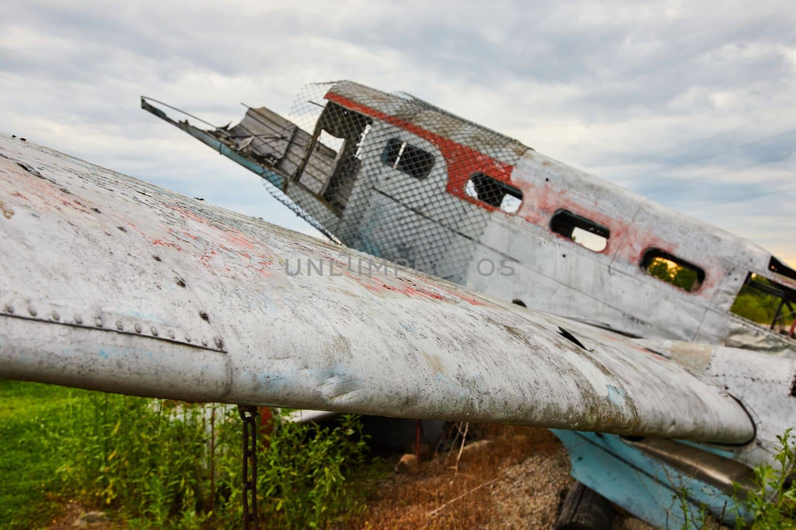 Crashed and abandoned airplane wing detail in fields on cloudy day by njproductions