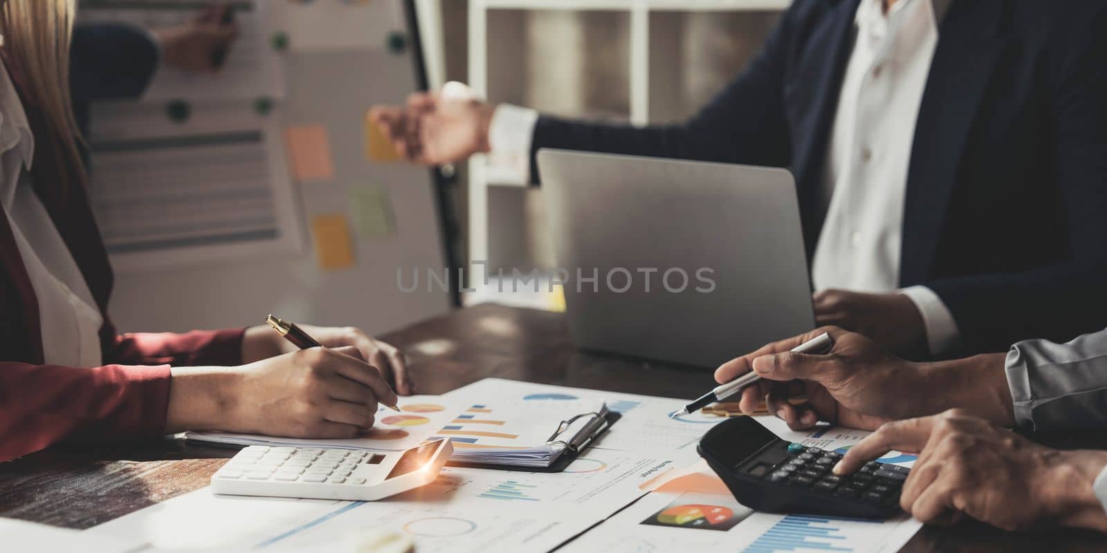 Business People Meeting using laptop computer,calculator,notebook,stock market chart paper for analysis Plans to improve quality next month. Conference Discussion Corporate Concept