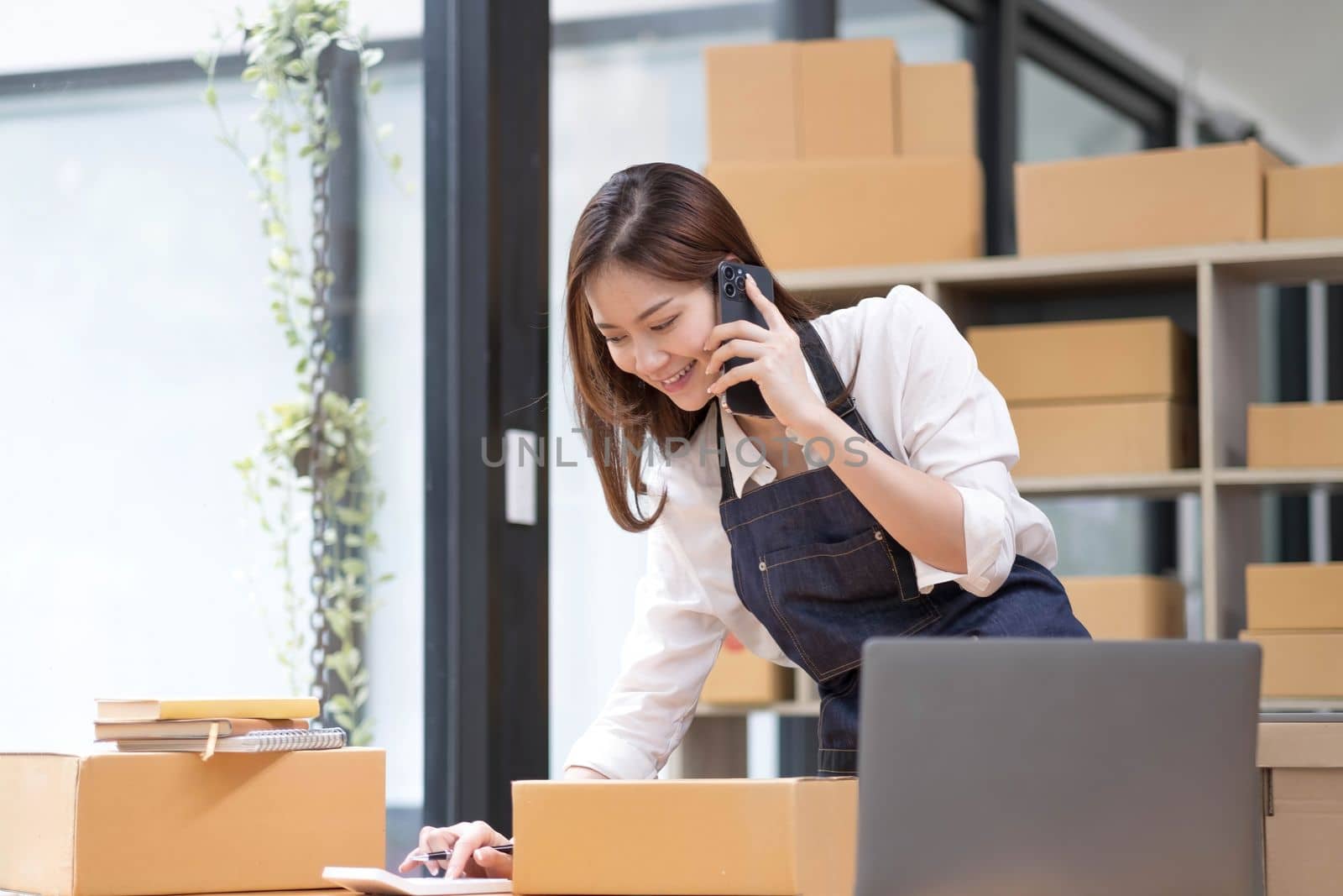 Young Asian Woman Working at home, Young Owner Woman talking to customer and working with happy emotion. People with online shopping SME entrepreneur or freelance working concept...